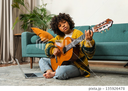 Blogger guitarist. Happy African American girl blogger playing guitar singing song recording vlog. Social media influencer woman streaming recording at home studio. Music content creator broadcast 135926478