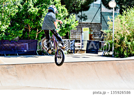 A young man practicing BMX and performing tricks at the skatepark.	 135926586