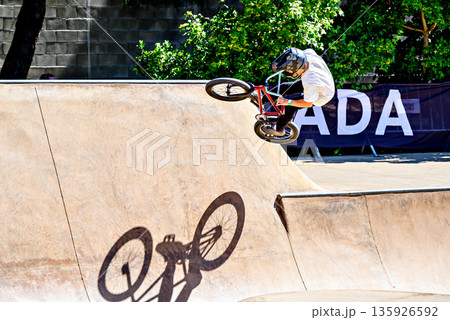 A young man practicing BMX and performing tricks at the skatepark.	 135926592