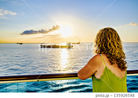 Woman looking at ships on the horizon at sunset	 135926598