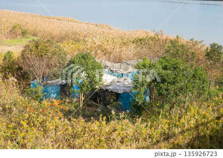 川沿いに建つホームレスの家、河原にある浮浪者のテント 川沿いに建つホームレスの家、河原にある浮浪者のテント 135926723