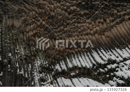 Vertical basalt columns create dense geometric textures at Symphony of Stones, dark volcanic rock contrasts with scattered snow Vertical basalt columns create dense geometric textures at Symphony of Stones, dark volcanic rock contrasts with scattered snow 135927326