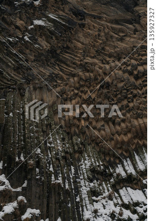 Vertical basalt columns create dense geometric textures at Symphony of Stones, dark volcanic rock contrasts with scattered snow 135927327