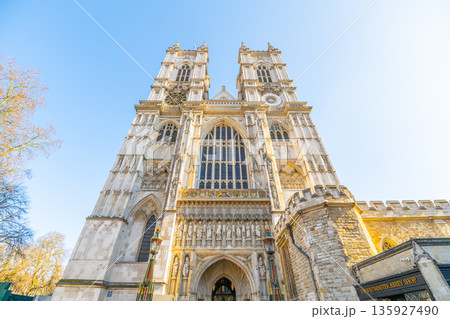 Westminster Abbey stands tall in London. The grand structure shows its detailed facade and towers. Visitors admire the historic site in the sunlight, capturing its notable features. Westminster Abbey stands tall in London. The grand structure shows its detailed facade and towers. Visitors admire the historic site in the sunlight, capturing its notable features. 135927490