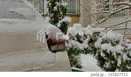 A thick layer of snow on the trees and a car parked in front of the house 135927513