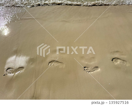 Barefoot Footprints on Wet Beach Sand 135927516