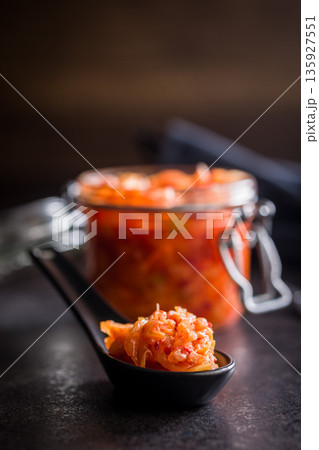 Fermented cabbage. Kimchi. Korean food in ceramic spoon on black table. Fermented cabbage. Kimchi. Korean food in ceramic spoon on black table. 135927551