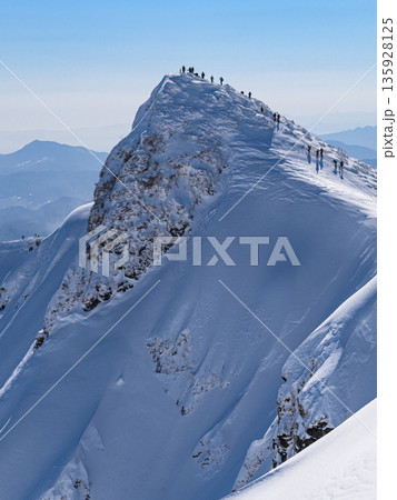 厳冬期の谷川岳 オキの耳から見るトマの耳と登山者のシルエット 135928125