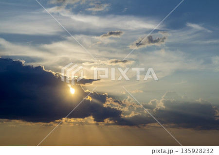 Panorama of sky at sunrise or sunset. Beautiful view of dark blue clouds lit by bright orange yellow sun on clear sky. Beauty and power of nature, meteorology and climate changing concept. Panorama of sky at sunrise or sunset. Beautiful view of dark blue clouds lit by bright orange yellow sun on clear sky. Beauty and power of nature, meteorology and climate changing concept. 135928232