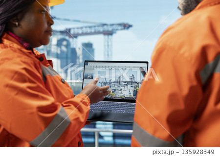 Close up of drilling rig engineering team using laptop software dashboard for anomaly detection during operation. Offshore platform coworkers use notebook program interface to control systems remotely 135928349