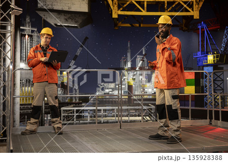 African american environmental engineer uses radio communication to inspect offshore drilling systems, ensuring efficient fuel production and compliance with oil and fuel extraction. African american environmental engineer uses radio communication to inspect offshore drilling systems, ensuring efficient fuel production and compliance with oil and fuel extraction. 135928388