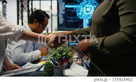 Programmer shaking hand with businessmen in tech agency boardroom. Angel investors meeting with AI startup company CTOs to hear technology presentation before investing, camera A Programmer shaking hand with businessmen in tech agency boardroom. Angel investors meeting with AI startup company CTOs to hear technology presentation before investing, camera A 135928402
