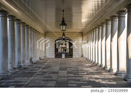 Visitors walk through the long corridor of Greenwich Queens House in London, lined with many columns and bathed in natural light during the daytime. Visitors walk through the long corridor of Greenwich Queens House in London, lined with many columns and bathed in natural light during the daytime. 135928999