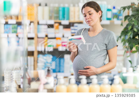 Pregnant woman choosing pills in pharmacy 135929385