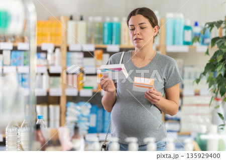 Pregnant woman choosing pills in pharmacy 135929400