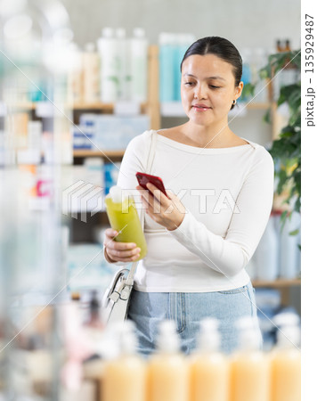 Asian woman scanning shampoo in pharmacy 135929487