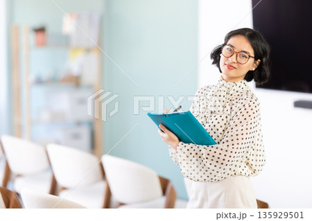 Young student takes notes in folder in lecture hall 135929501