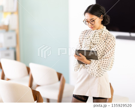 Young woman student taking notes on tablet in lecture hall 135929520
