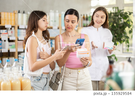 Mother and daughter scan qr code of pills with pharmacist Mother and daughter scan qr code of pills with pharmacist 135929584