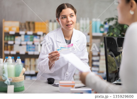 Pharmacist processing order for female customer at pharmacy Pharmacist processing order for female customer at pharmacy 135929600