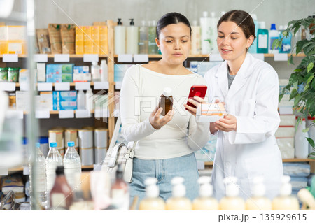 Woman checking composition of medication online at pharmacy 135929615
