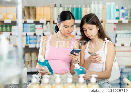 Woman and daughter scanning barcode on mouthwash Woman and daughter scanning barcode on mouthwash 135929719
