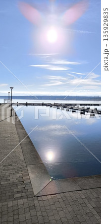 Bright sun reflecting on smooth water, sun, clouds, pier, embankment 135929835