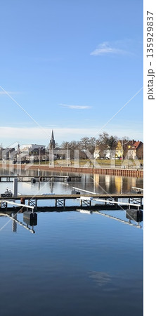 City pier for boats, yachts, sailboats. Blue sky and mirror-like surface of the lake City pier for boats, yachts, sailboats. Blue sky and mirror-like surface of the lake 135929837