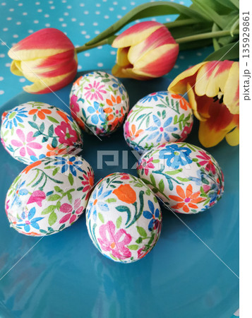 Bright floral printed Easter eggs with orange tulips on turquoise background. Bright floral printed Easter eggs with orange tulips on turquoise background. 135929861