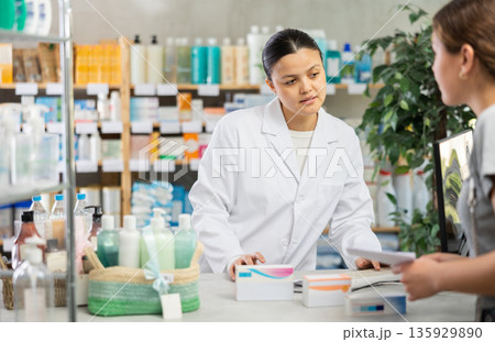 Pharmacist recommending medicines to woman at drugstore counter Pharmacist recommending medicines to woman at drugstore counter 135929890