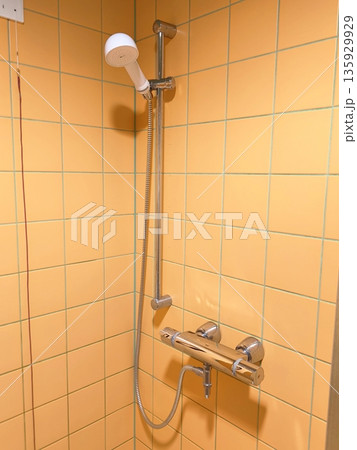 A modern handheld shower with hoses and a thermostatic mixer tap in the shower stall. A modern handheld shower with hoses and a thermostatic mixer tap in the shower stall. 135929929