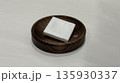 White bar soap on wooden soap dish on white surface, close-up 135930337