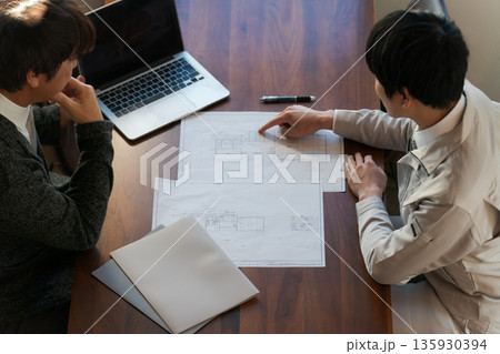 図面を見て打ち合わせをする男性 135930394