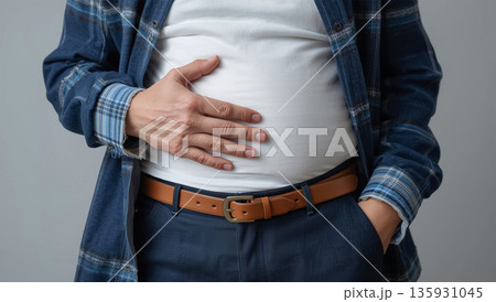 男性が室内でお腹に手を当てて立つ日中の近接ポートレート 135931045