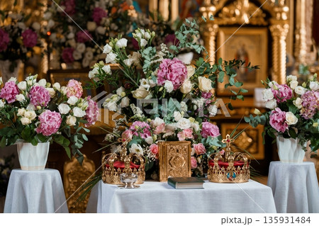 Ornate Church Altar Decorated with Pink and White Flowers, Gold Crowns, and Religious Icons in a Sacred Setting 135931484