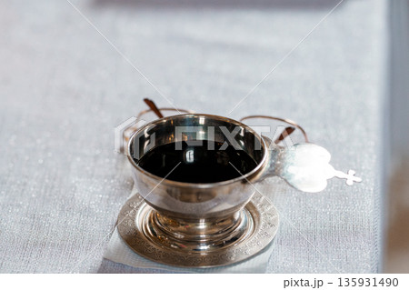Silver Chalice with Holy Wine on White Linen Tablecloth, Religious Ceremony, Minimalist Still Life, Close-Up View Silver Chalice with Holy Wine on White Linen Tablecloth, Religious Ceremony, Minimalist Still Life, Close-Up View 135931490
