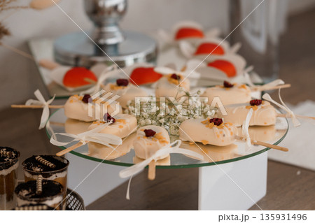 Elegant White Chocolate Desserts with Cranberries and Baby's Breath on Glass Stand at Wedding Reception 135931496