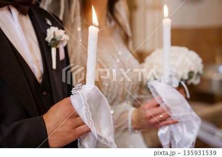Romantic Wedding Couple Holding Lit Candles in Elegant Church Ceremony with Soft Warm Lighting and White Lace Details Romantic Wedding Couple Holding Lit Candles in Elegant Church Ceremony with Soft Warm Lighting and White Lace Details 135931539
