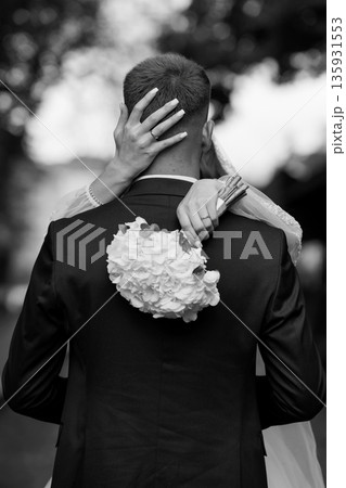 Black and White Wedding Moment of Bride Hugging Groom from Behind with Bouquet and Ring Visible Black and White Wedding Moment of Bride Hugging Groom from Behind with Bouquet and Ring Visible 135931553