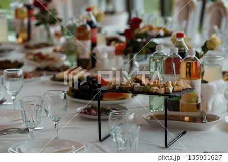 Elegant Buffet Table Setup with Cheese Platter, Fresh Fruits, Flowers, and Drinks for a Luxurious Wedding or Banquet Event 135931627