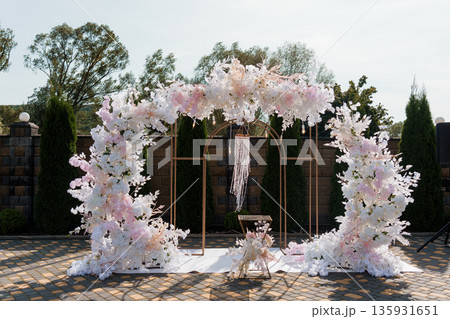 Elegant Wedding Arch Decorated with White and Pink Flowers and Beaded Drapery in Outdoor Garden Setting Elegant Wedding Arch Decorated with White and Pink Flowers and Beaded Drapery in Outdoor Garden Setting 135931651