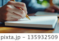 ノートに文字を書く手元のクローズアップと金色のペン 135932509