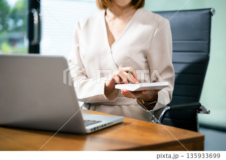 Women counting coins on calculator taking from the piggy bank. hand holding pen working on calculator to calculate on desk 135933699