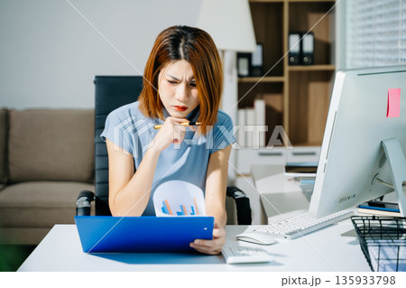 Asian woman feeling migraine head strain.Overworked businesswoman financier while working on laptop and tablet at office. Asian woman feeling migraine head strain.Overworked businesswoman financier while working on laptop and tablet at office. 135933798