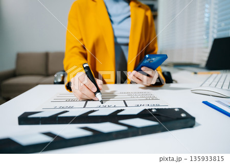 Creative female filmmaker working with tablet, clapperboard, and laptop in modern studio office. Film production, planning, and content creation scene. Creative female filmmaker working with tablet, clapperboard, and laptop in modern studio office. Film production, planning, and content creation scene. 135933815