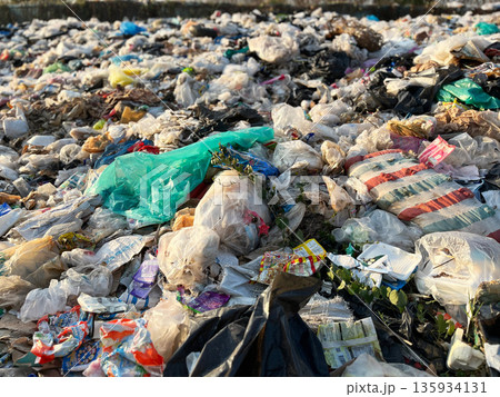 Large pile of plastic waste and garbage bags at an open dumpsite, highlighting plastic pollution, environmental damage, waste management problems, recycling crisis, sustainability issues, and global e Large pile of plastic waste and garbage bags at an open dumpsite, highlighting plastic pollution, environmental damage, waste management problems, recycling crisis, sustainability issues, and global e 135934131