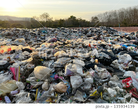 landfill filled with plastic waste and garbage, the contrast between natural beauty, human pollution, highlighting environmental crisis, overconsumption, sustainability issues, climate impact 135934139