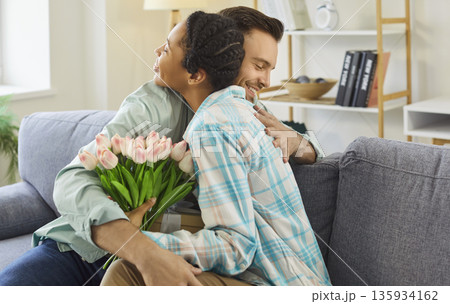 Happy woman hugs her boyfriend thanking him for a gift and flowers Happy woman hugs her boyfriend thanking him for a gift and flowers 135934162