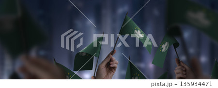 Macao flags in their hands on a blurred urban background Macao flags in their hands on a blurred urban background 135934471