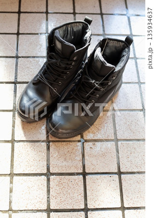 濡れたタイルの上に置いてあるメンズのスノーブーツ 135934637